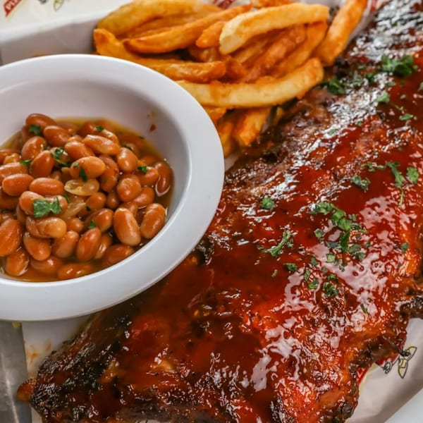Stevie Tomato's BBQ ribs with baked beans and french fries on a white paper-lined tray.