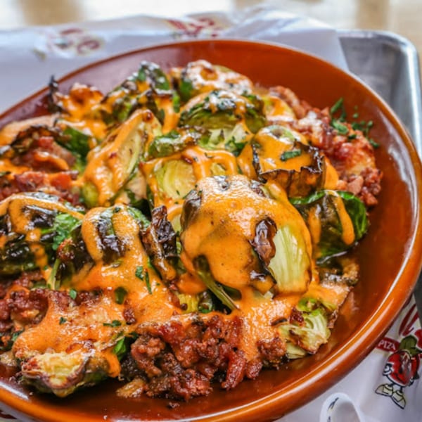 Roasted Brussels sprouts with melted cheese and bacon bits in a brown bowl at Stevie Tomato's.