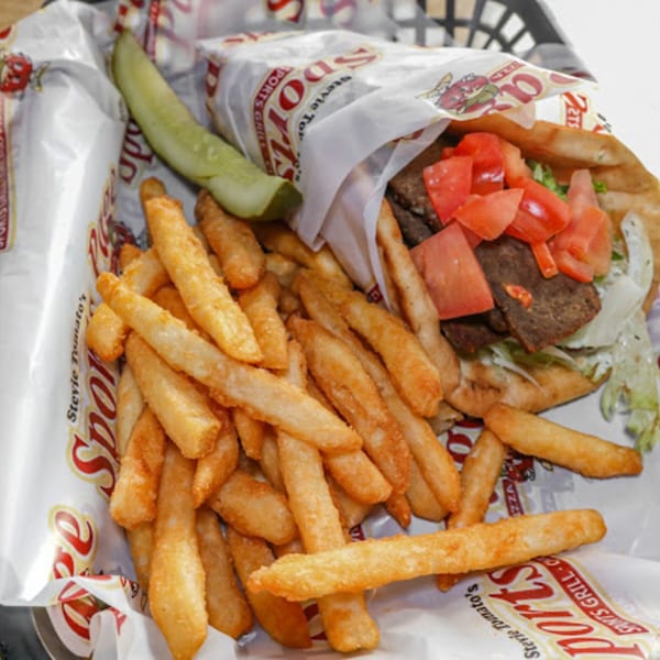 A Stevie Tomato's gyro with tomatoes, lettuce, and meat, served with fries and a pickle spear.