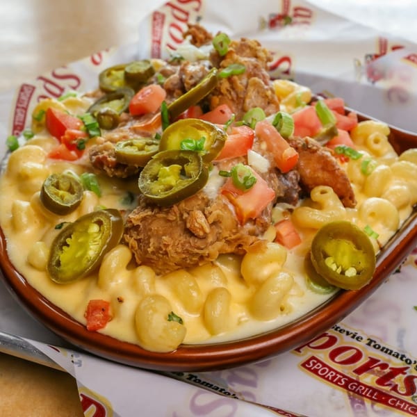 Stevie Tomato's mac and cheese topped with fried chicken, jalapeños, tomatoes, and green onions.