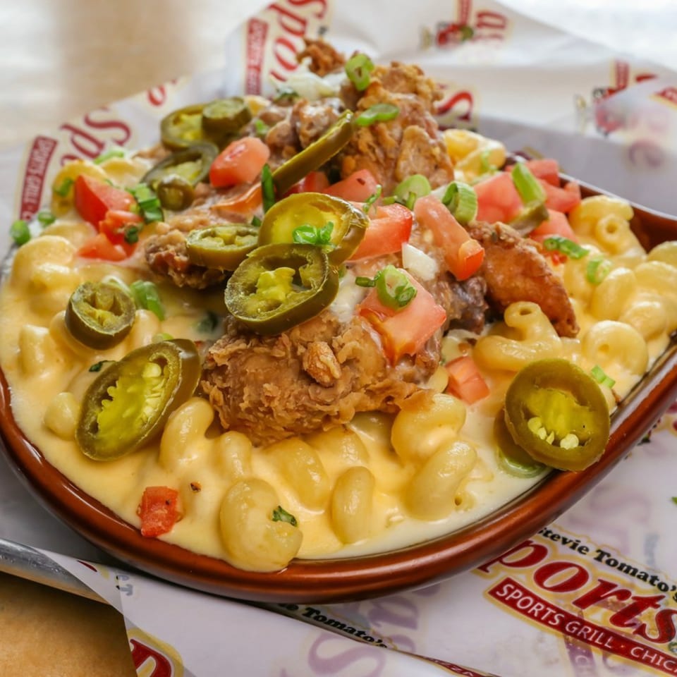 Stevie Tomato's mac and cheese topped with fried chicken, jalapeños, tomatoes, and green onions.