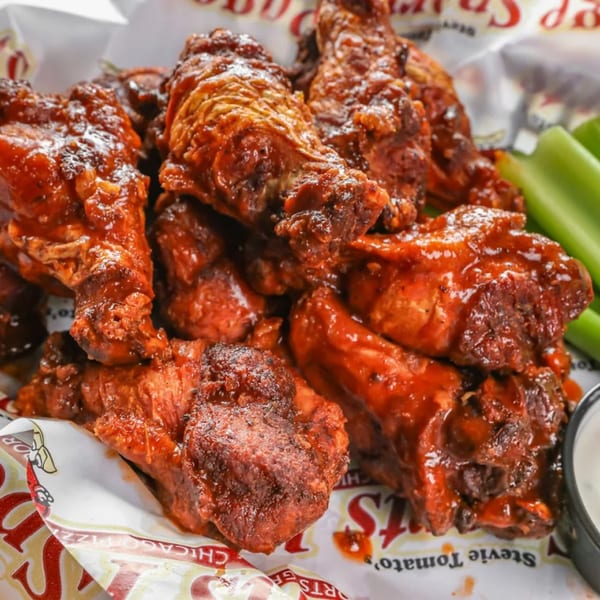 Close-up of Stevie Tomato's spicy chicken wings with celery sticks and ranch dressing.