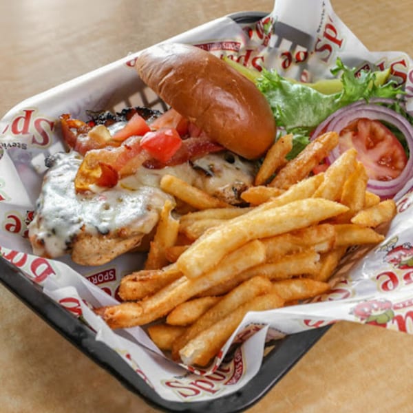 A Stevie Tomato's chicken sandwich with melted cheese, bacon, and tomatoes, served with fries.